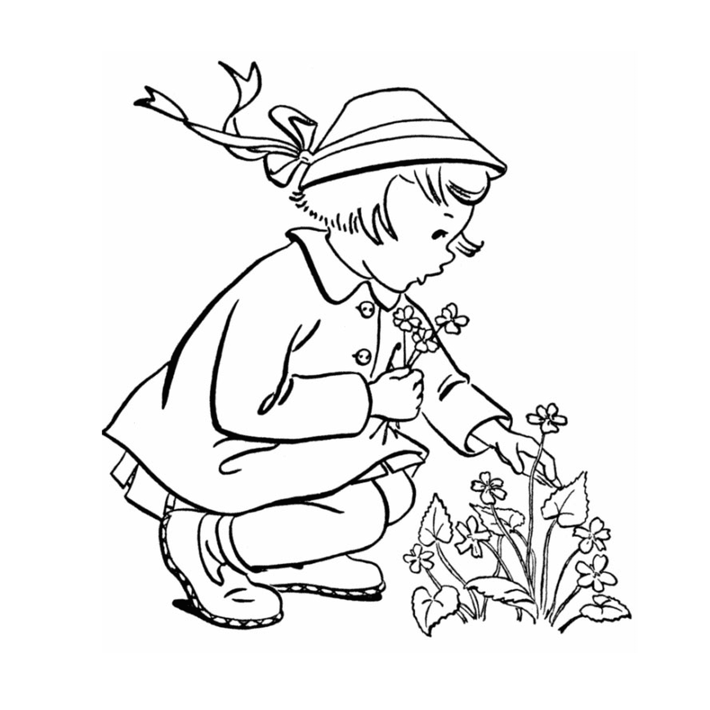  Ein kleines Mädchen kniet, um eine Blume zu pflanzen 